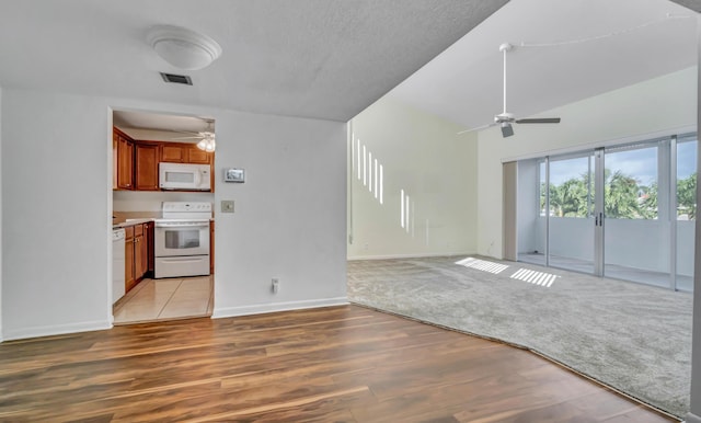 unfurnished living room with ceiling fan, vaulted ceiling, light carpet, and french doors