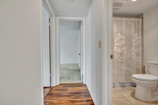 bathroom featuring curtained shower, toilet, and wood-type flooring