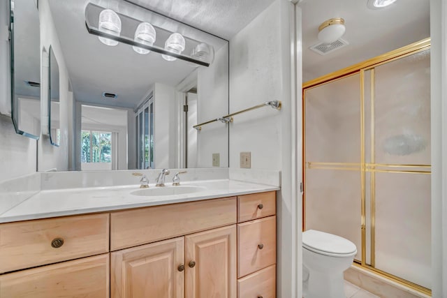 bathroom featuring tile patterned flooring, toilet, an enclosed shower, and vanity