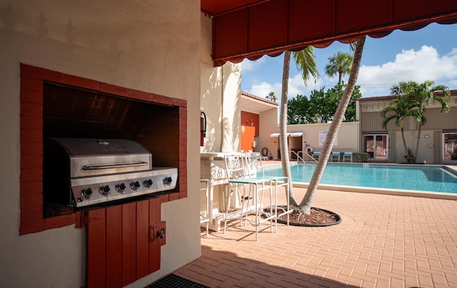 view of pool with a grill and a patio area