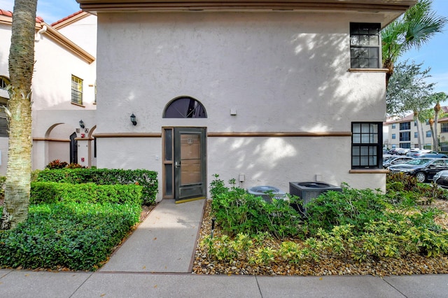 doorway to property with central AC and stucco siding