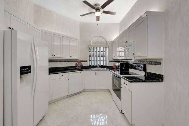 kitchen with white appliances, tasteful backsplash, white cabinets, a ceiling fan, and a sink