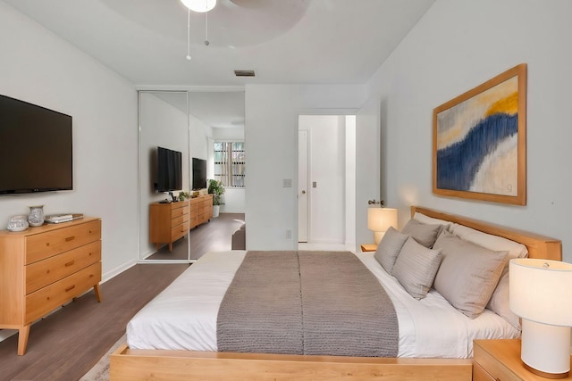 bedroom with dark wood-type flooring, a closet, visible vents, and ceiling fan