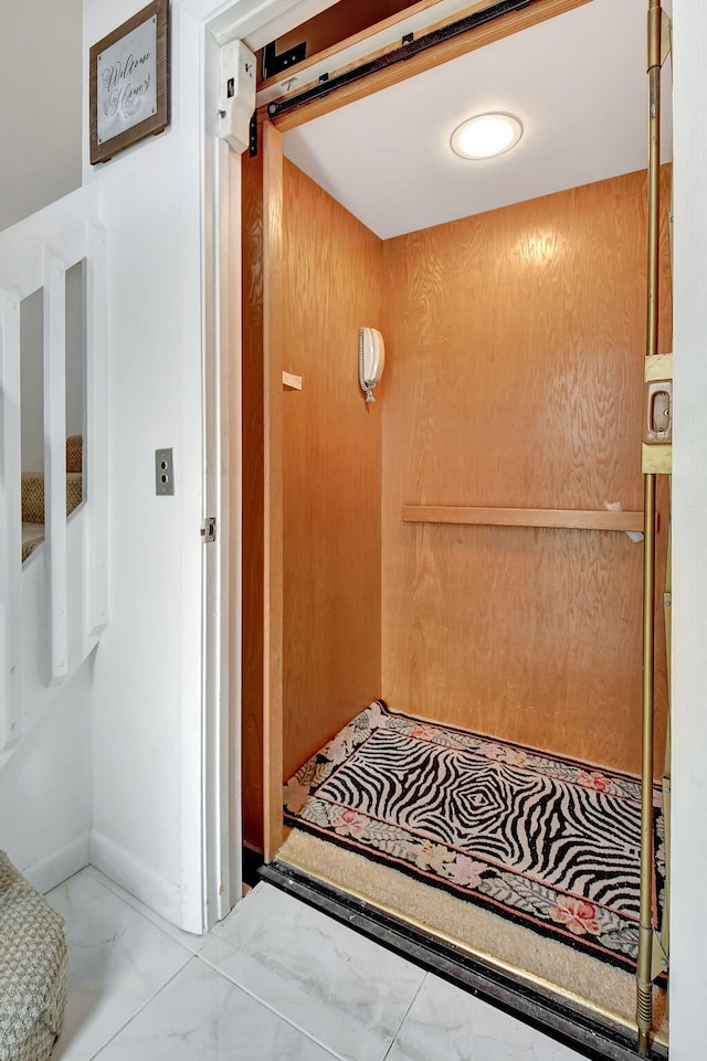 interior space featuring baseboards, marble finish floor, and elevator