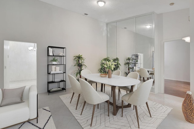 dining room with light tile patterned floors, visible vents, and a textured ceiling