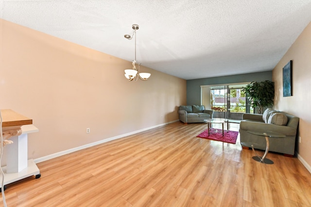 living room featuring a textured ceiling, a notable chandelier, and light hardwood / wood-style floors