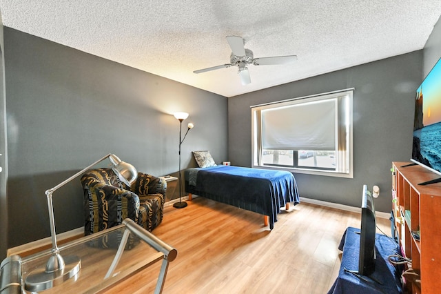 bedroom with ceiling fan, a textured ceiling, and hardwood / wood-style floors