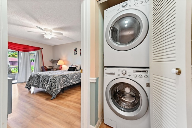 laundry room with ceiling fan, a textured ceiling, stacked washer and clothes dryer, and hardwood / wood-style floors