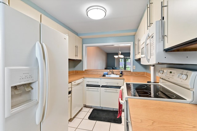 kitchen featuring white appliances, light tile patterned flooring, pendant lighting, sink, and white cabinetry