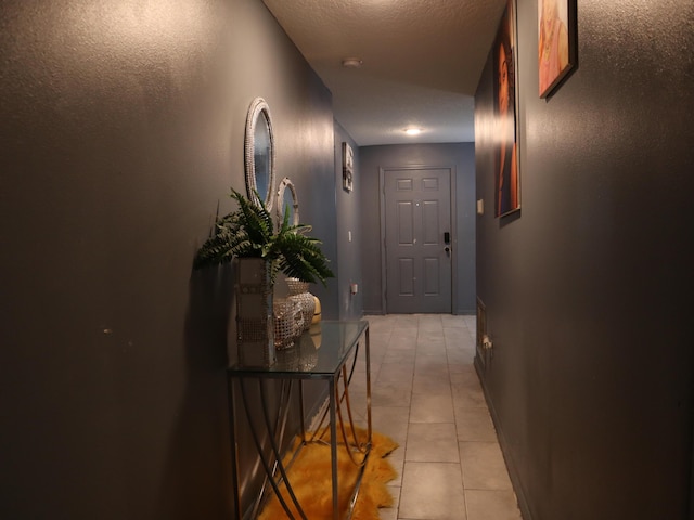 hall featuring light tile patterned floors and a textured ceiling