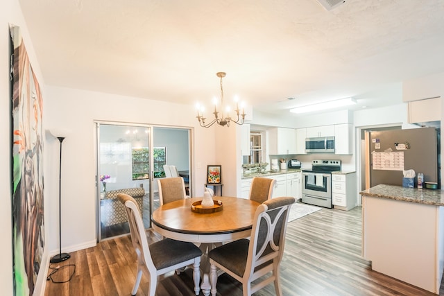 dining space with hardwood / wood-style flooring and a notable chandelier