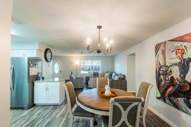 dining area with light hardwood / wood-style floors and a chandelier