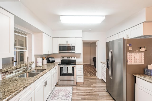 kitchen featuring light stone countertops, white cabinetry, sink, and appliances with stainless steel finishes