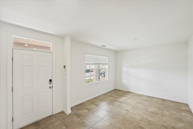 entryway featuring light tile patterned floors and a textured ceiling