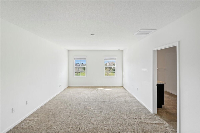 empty room with a textured ceiling and light carpet