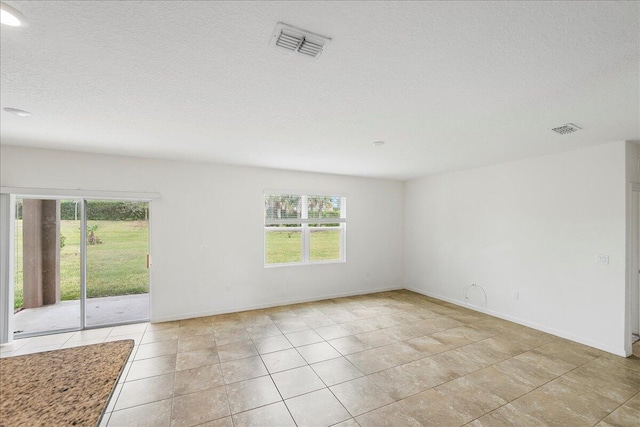 empty room with light tile patterned floors and a textured ceiling