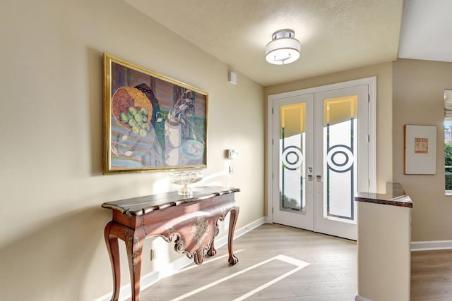 foyer featuring a wealth of natural light, light hardwood / wood-style flooring, a textured ceiling, and french doors