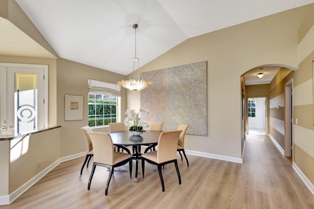 dining space with lofted ceiling, a chandelier, and light hardwood / wood-style flooring