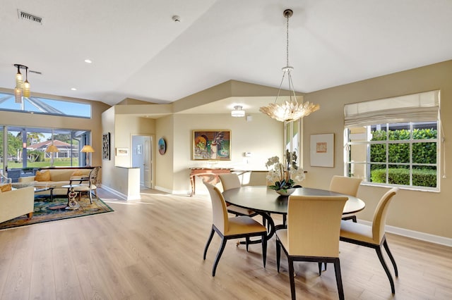 dining space with light wood-type flooring, an inviting chandelier, and lofted ceiling