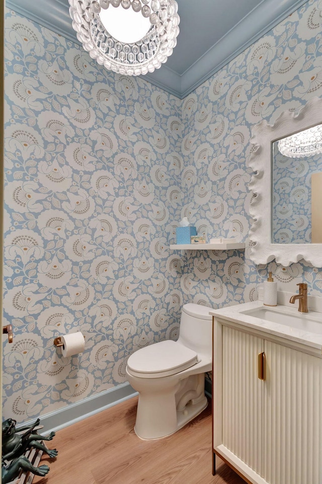 bathroom featuring wood-type flooring, toilet, vanity, and ornamental molding