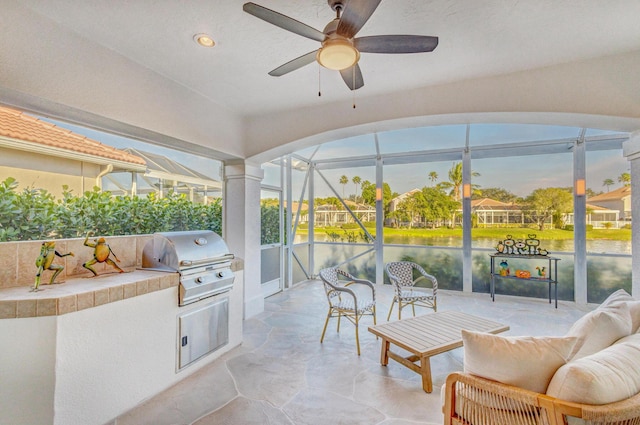 view of patio with exterior kitchen, ceiling fan, glass enclosure, and area for grilling