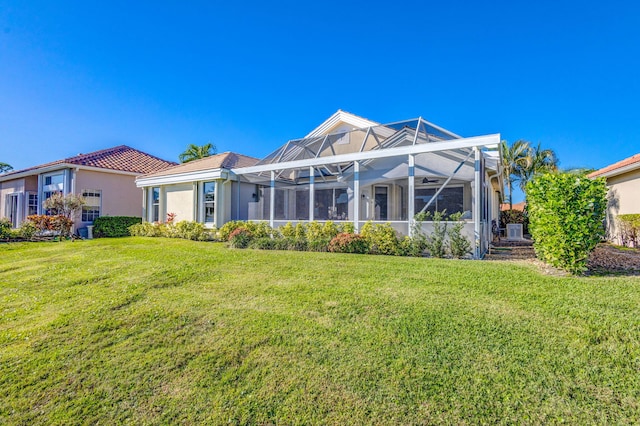 rear view of property featuring glass enclosure and a yard