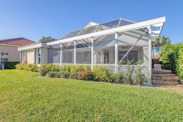 back of house with a lanai, ceiling fan, and a yard