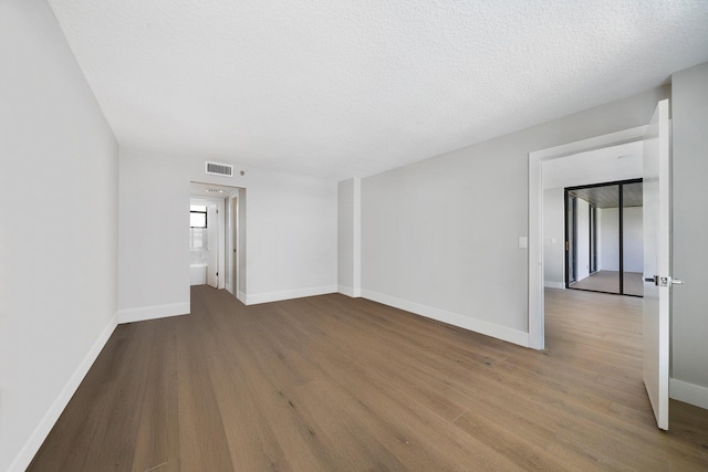 spare room with a textured ceiling and light hardwood / wood-style flooring