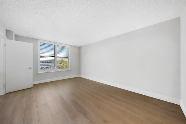 empty room with wood-type flooring and a textured ceiling