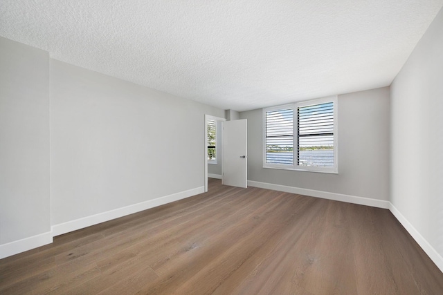 unfurnished room with a textured ceiling and dark wood-type flooring