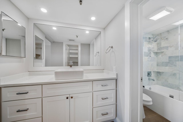 full bathroom with vanity, wood-type flooring, tiled shower / bath combo, and toilet