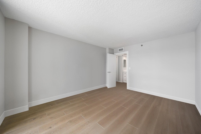 unfurnished room with light hardwood / wood-style floors and a textured ceiling