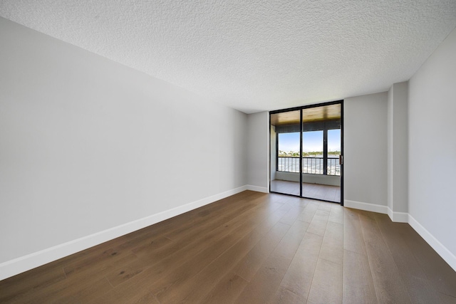 unfurnished room featuring a textured ceiling, expansive windows, and dark wood-type flooring