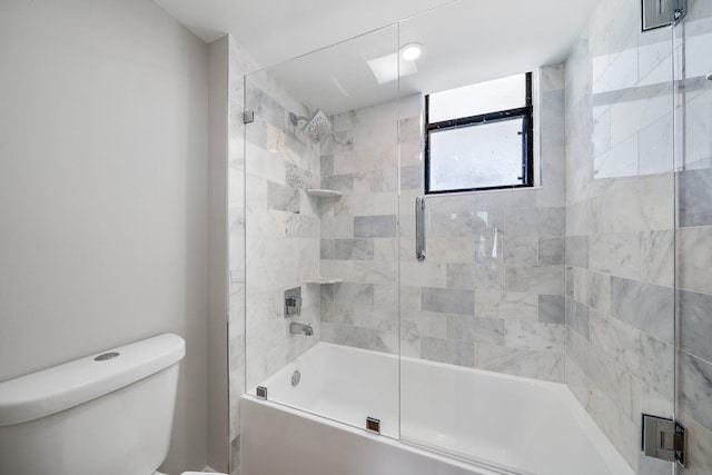 bathroom with toilet and bath / shower combo with glass door