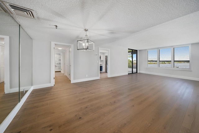 unfurnished living room featuring dark hardwood / wood-style flooring, a chandelier, and a textured ceiling