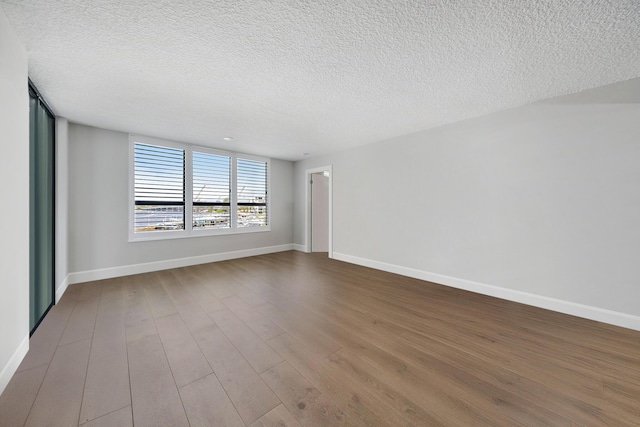 empty room featuring wood-type flooring and a textured ceiling