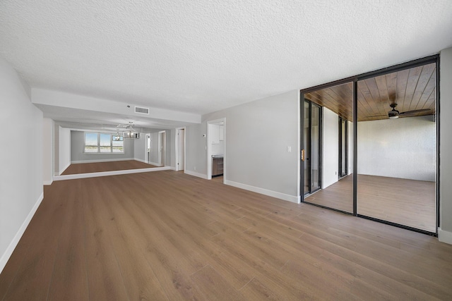 unfurnished living room featuring ceiling fan, light wood-type flooring, and a textured ceiling