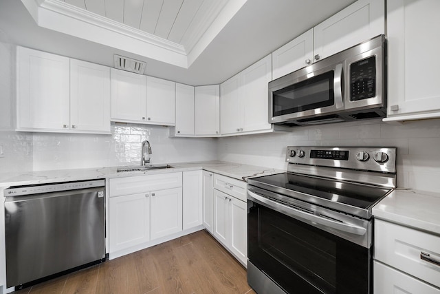 kitchen with sink, white cabinets, ornamental molding, and appliances with stainless steel finishes