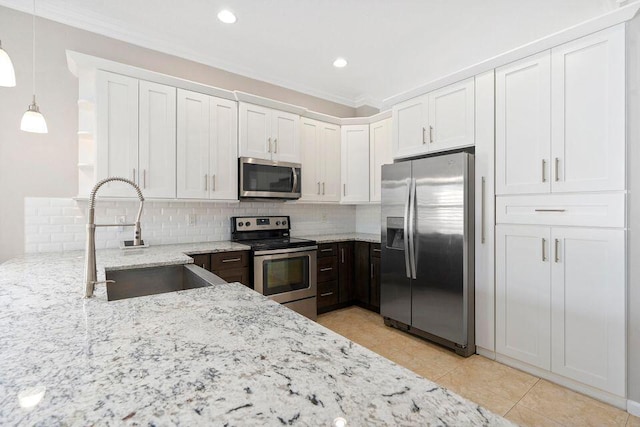 kitchen featuring light stone counters, stainless steel appliances, sink, white cabinets, and hanging light fixtures