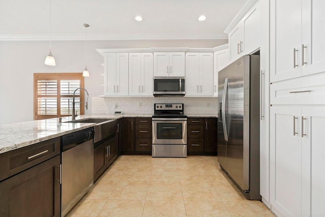 kitchen with light stone countertops, stainless steel appliances, sink, pendant lighting, and white cabinetry