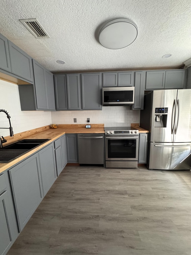 kitchen featuring gray cabinetry, light hardwood / wood-style floors, sink, and stainless steel appliances