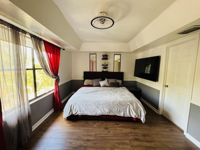 bedroom with dark hardwood / wood-style floors and a tray ceiling