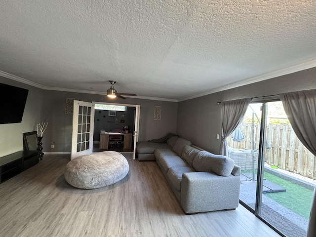 living room featuring hardwood / wood-style flooring, ceiling fan, ornamental molding, and a textured ceiling