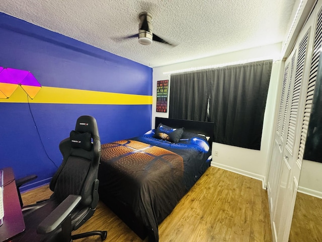 bedroom with hardwood / wood-style floors, ceiling fan, and a textured ceiling