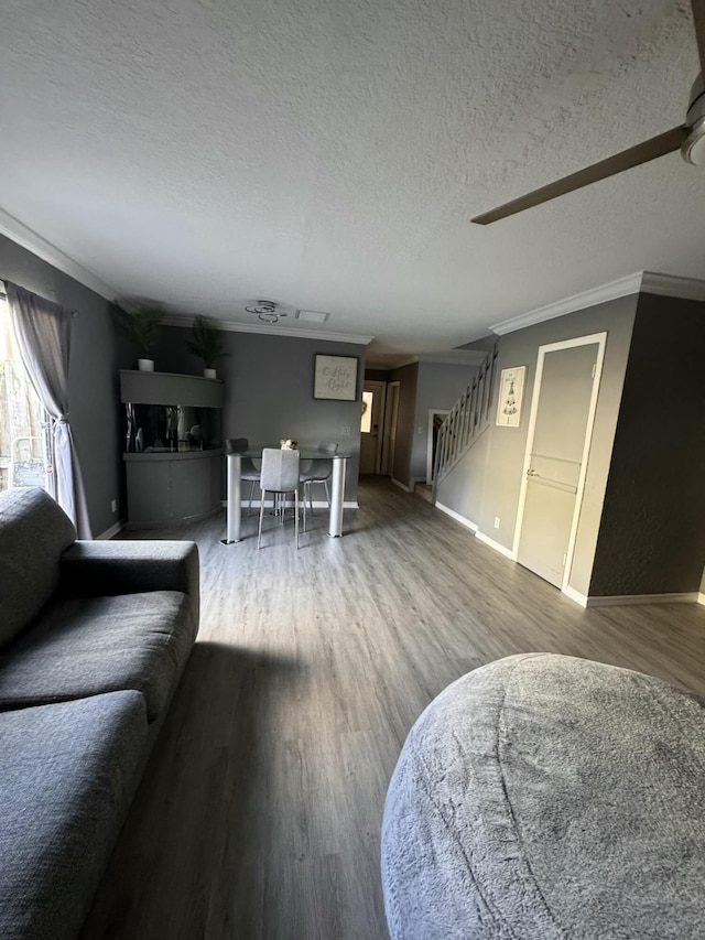 living room with ceiling fan, hardwood / wood-style floors, a textured ceiling, and ornamental molding