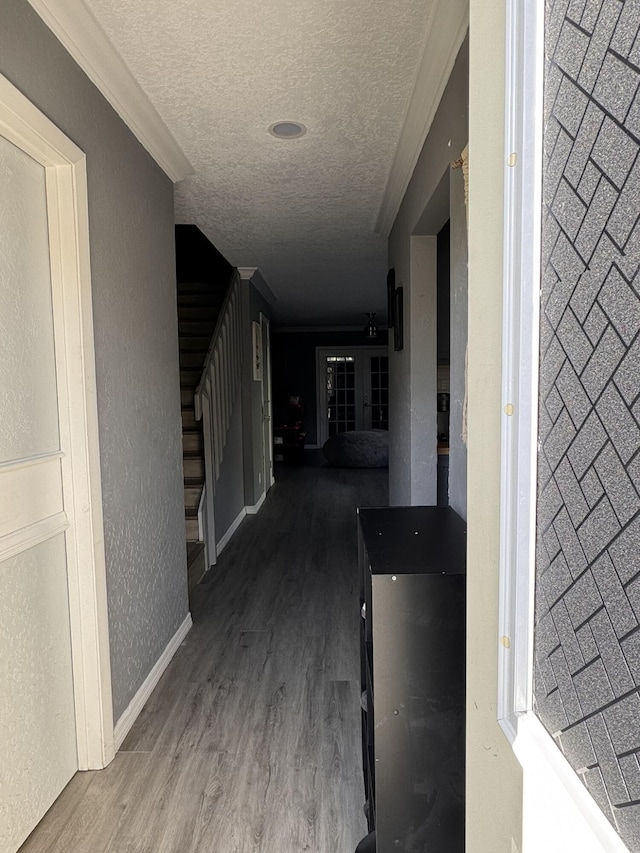 hallway featuring a textured ceiling, wood-type flooring, and crown molding