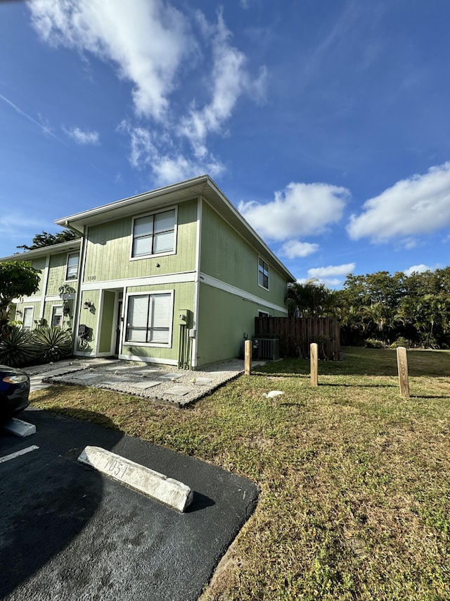 rear view of house featuring cooling unit and a yard