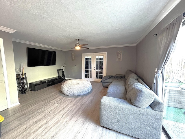 living room with wood-type flooring, a textured ceiling, french doors, and ornamental molding