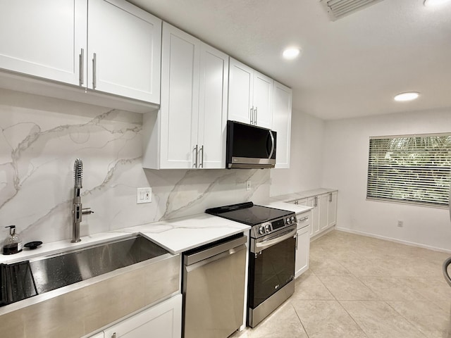 kitchen featuring white cabinets, stainless steel appliances, decorative backsplash, sink, and light stone counters