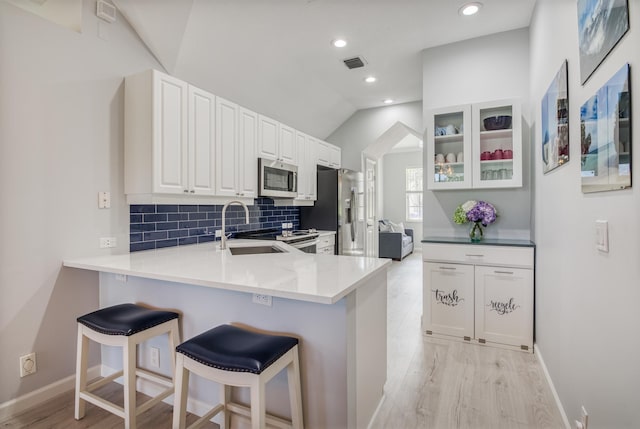 kitchen with sink, stainless steel appliances, tasteful backsplash, kitchen peninsula, and white cabinets